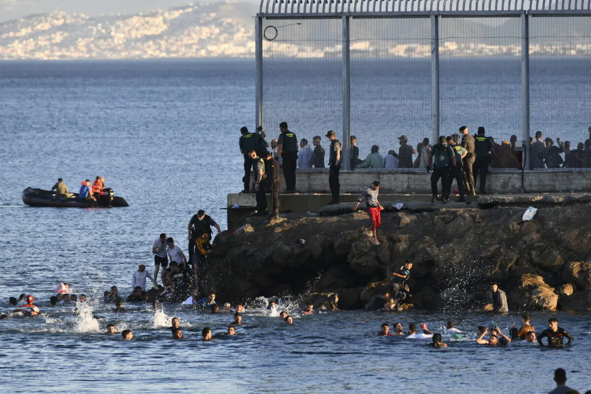 Spanish Guardia Civil officers try to stop people from Morocco swimming and entering into the Spanish territory at the border of Morocco and Spain, at the Spanish enclave of Ceuta, on May 17, 2021. (Antonio Sempere/Europa Press via AP)