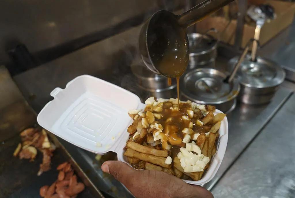 A cook prepares a poutine at La Banquise restaurant in Montreal on Tuesday, May 18, 2021. The Quebec dairy industry trying to get a protected trademark for the popular Quebecois dish. (Paul Chiasson/The Canadian Press)