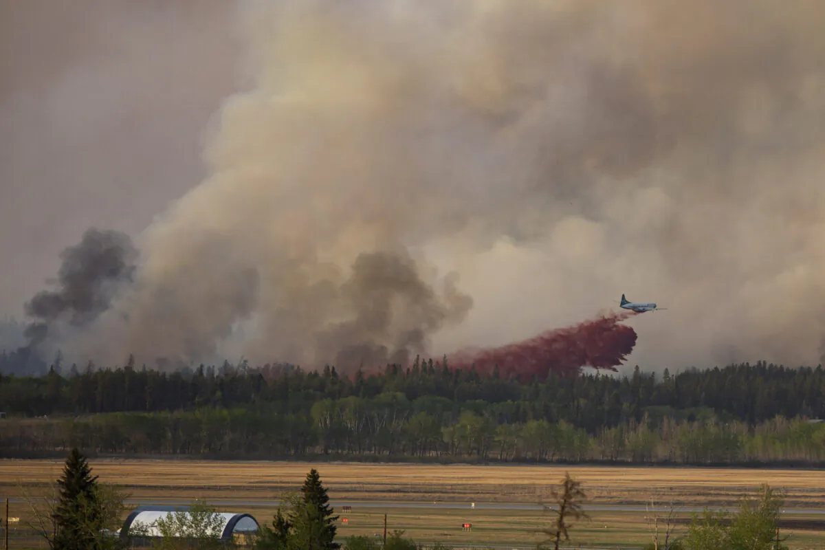 Fire crews drop fire retardant from the air near a forest fire burning northeast of the city in Prince Albert, Sask., Monday, May 17, 2021. The northern Saskatchewan city has declared a local state of emergency due to a wildfire that's fast-moving and forcing some residents to flee for safety. (Kayle Neis/The Canadian Press)