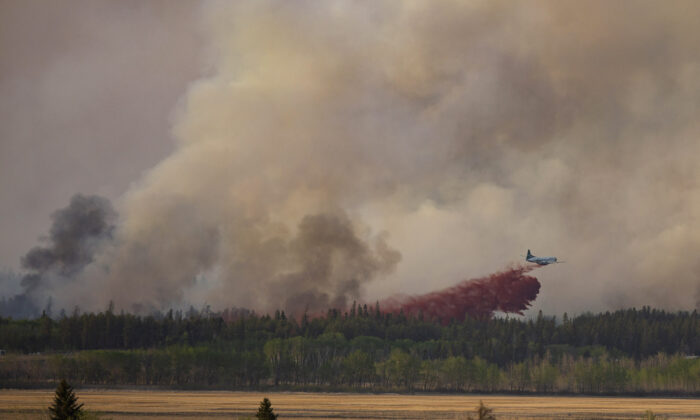 Fire crews drop fire retardant from the air near a forest fire burning northeast of the city in Prince Albert, Sask., Monday, May 17, 2021. The northern Saskatchewan city has declared a local state of emergency due to a wildfire that's fast-moving and forcing some residents to flee for safety. (Kayle Neis/The Canadian Press)