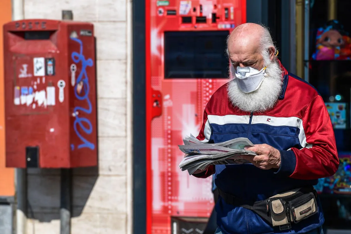 A resident wearing a face mask exits a shop after buying a newspaper in Treviolo, Italy, on April 9, 2020. (Miguel Medina/AFP via Getty Images)