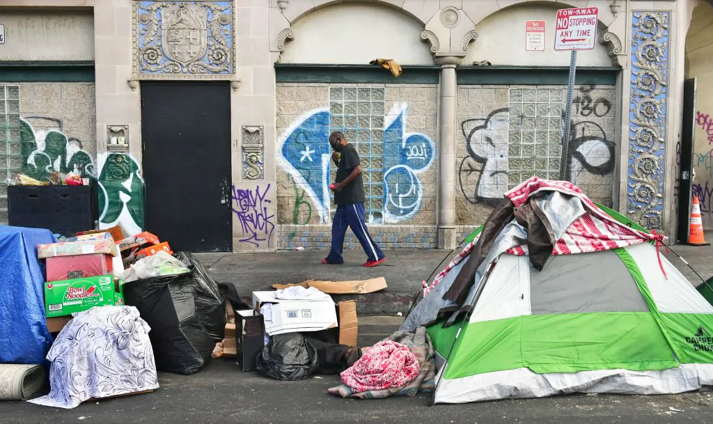 A man walks past tents housing the homeless on the streets in the Skid Row community of Los Angeles, Calif. on April 26, 2021. (Frederic J. Brown/AFP via Getty Images)
