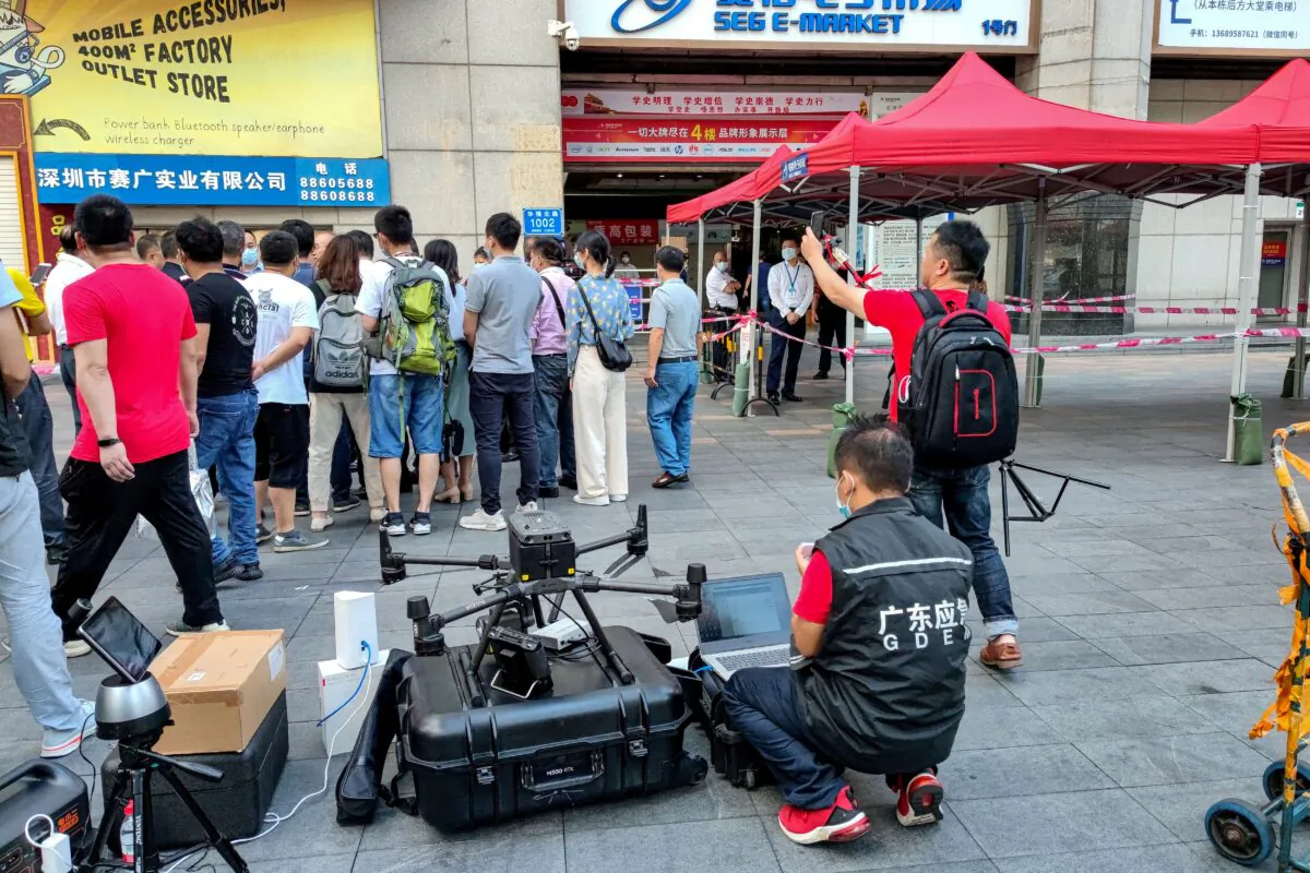 A staff member of the Emergency Management Department (front) works with a drone in front of the SEG Plaza in Shenzhen, China, on May 19, 2021, a day after it triggered widespread panic when it began shaking and was evacuated. (AFP via Getty Images)