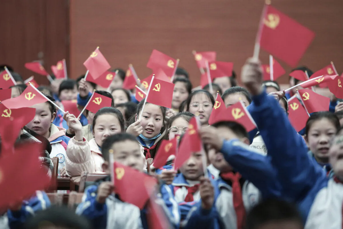 Students wave flags of the Communist Party as they prepare to watch a movie "The Founding of a Party" in Yangzhou, Jiangsu Province, on March 23, 2021. (STR/AFP via Getty Images)