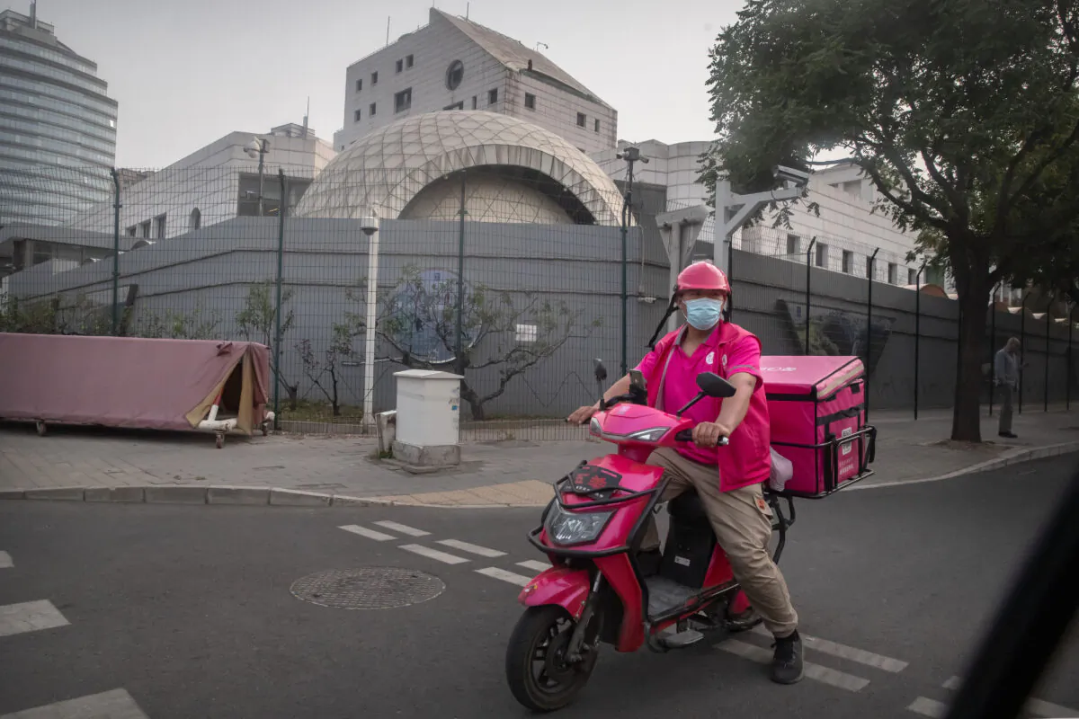 A delivery driver waits to cross an intersection near the Israeli Embassy in Beijing, on May 19, 2021. (Mark Schiefelbein/AP Photo)