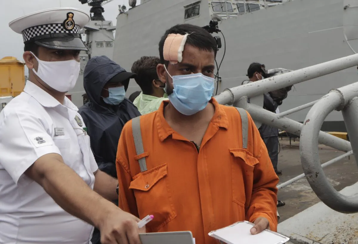 People rescued by the Indian navy from a barge that sank in the Arabian sea walk out from Indian naval ship INS Kochi in Mumbai, India, on May 19, 2021. (Rajanish Kakade/AP Photo)