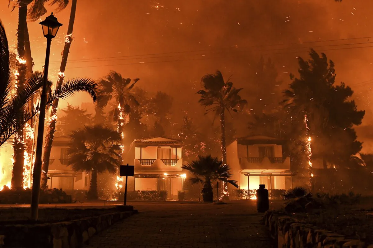 Fire burns among houses during a wildfire in the village of Schinos, near Corinth, Greece, on May 19, 2021. (Valerie Gache/AP Photo)