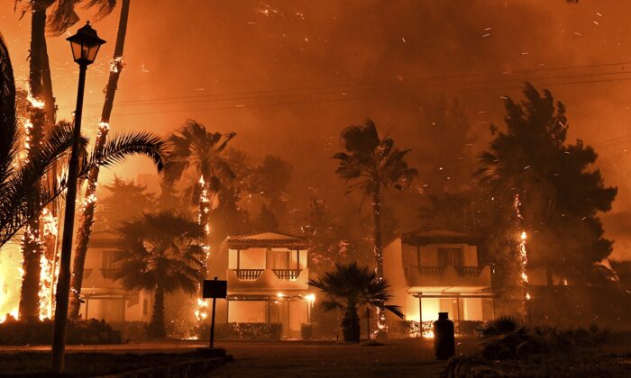 Fire burns among houses during a wildfire in the village of Schinos, near Corinth, Greece, on May 19, 2021. (Valerie Gache/AP Photo)