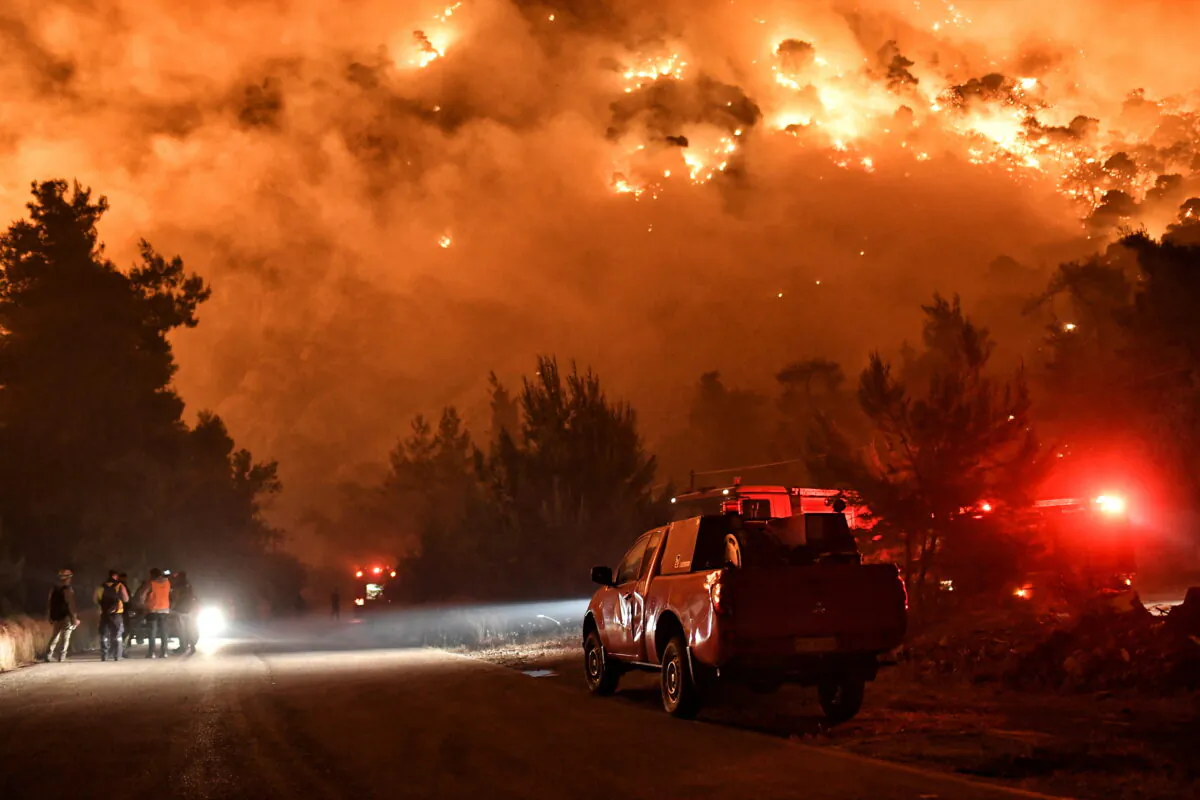 Flames rise as firefighters and volunteers try to extinguish a fire burning in the village of Schinos, near Corinth, Greece on May 19, 2021. (Vassilis Psomas/Reuters)