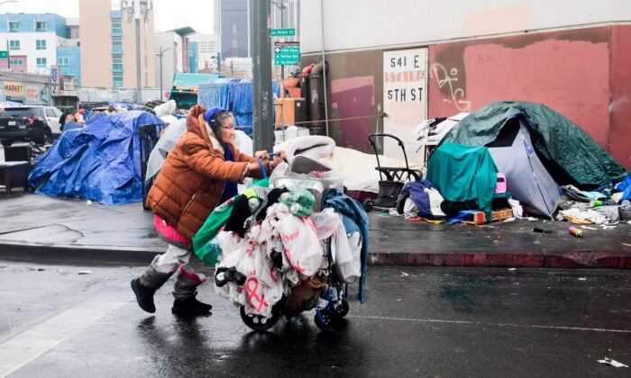 A homeless woman pushes her belongings past a row of tents on the streets of Los Angeles, Calif. on Feb. 1, 2021. (Frederic J. Brown/AFP via Getty Images)