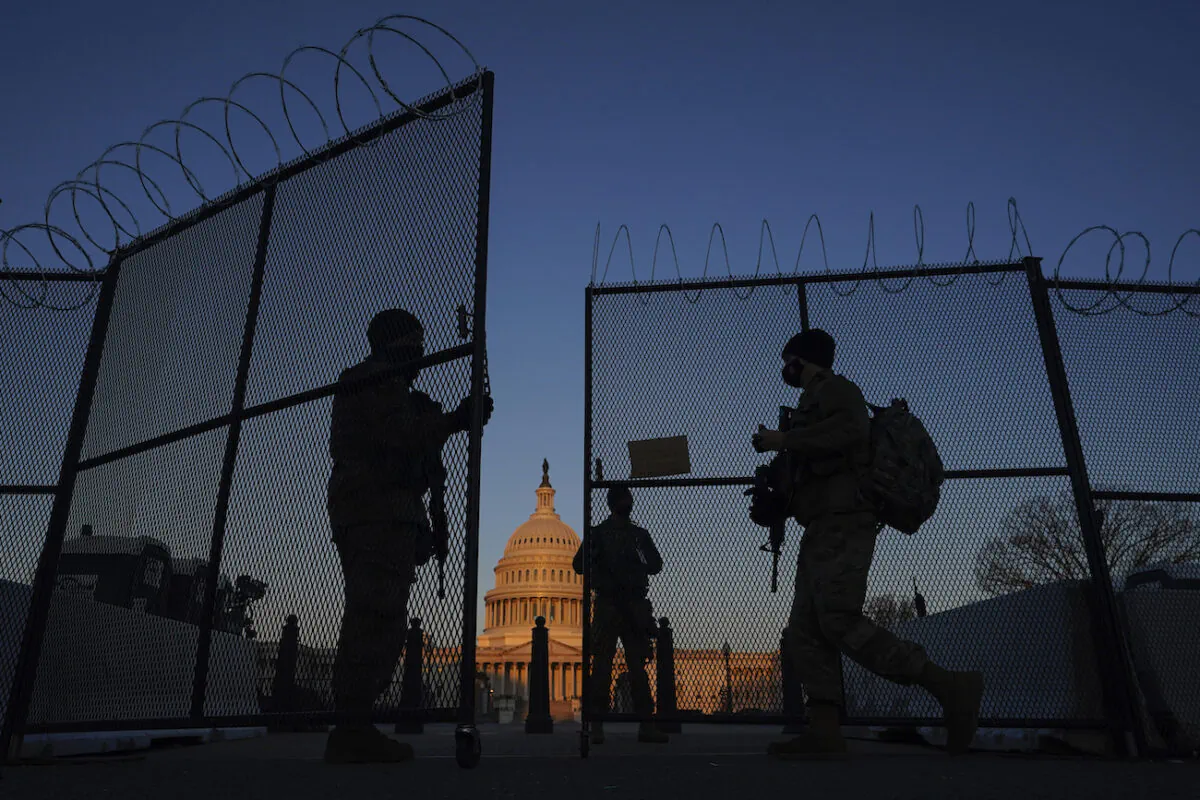 Members of the National Guard open a gate in the razor wire topped perimeter fence around the Capitol at sunrise in Washington, on March 8, 2021. (AP Photo/Carolyn Kaster)