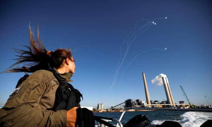 An Israeli soldier looks on as Israel's Iron Dome anti-missile system intercepts rockets launched from the Gaza Strip toward Israel, on May 19, 2021. (Amir Cohen/Reuters)