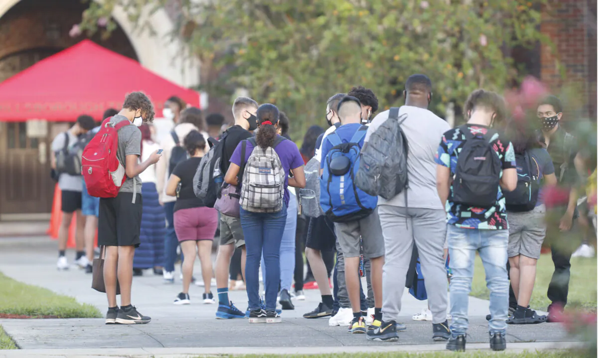 High school students wait in line to have temperature checked before entering campus in a file photo. (Octavio Jones/Getty Images)