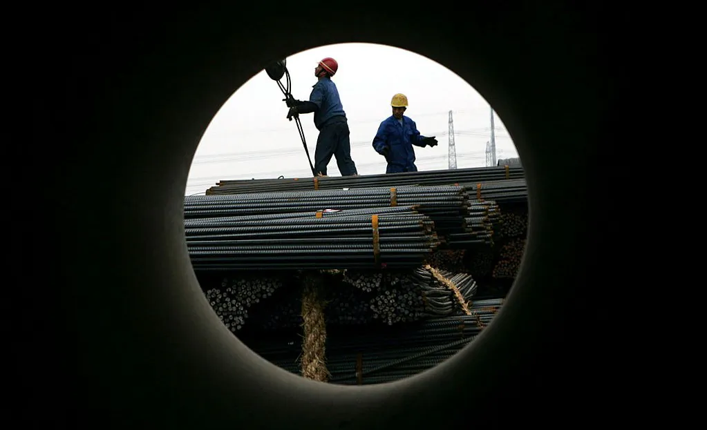 Workers unload steel at a steel products exchange market in Shanghai, China, on Apr. 6, 2005. (China Photos/Getty Images)