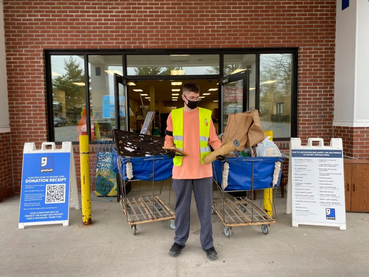 A donation attendant working for Goodwill Northern New England at the Westbrook, store looks at a broken picture frame and a broken cat scratching post, Maine, in an undated photo. (Heather Steeves/Goodwill Northern New England via AP)