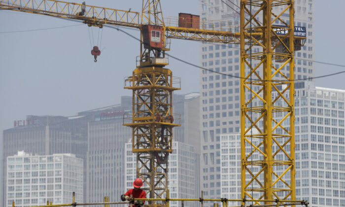 A worker fixes scaffolding at a construction site of a new real estate project in Beijing on June 11, 2009. (Liu Jin/AFP via Getty Images)