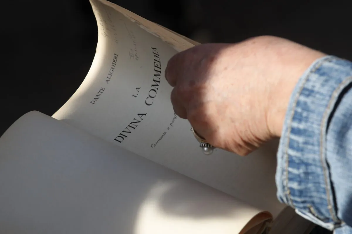 Ravenna citizen Giuliana Turati holds a copy of the Divina Commedia "Divine Comedy" by poet Dante Alighieri as she listens to a reading by volunteer Carlotta Zangolli in front of Alighieri's tomb, in Ravenna, Italy, on May 8, 2021. (Antonio Calanni/AP Photo)