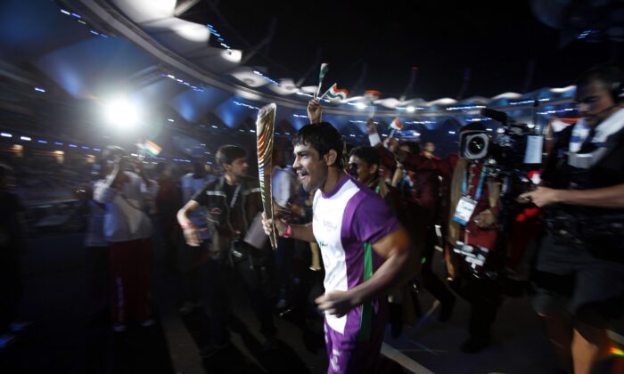 Indian wrestler Sushil Kumar runs as he holds the Queen's Baton during the opening ceremony for the Commonwealth Games at the Jawaharlal Nehru Stadium in New Delhi, on Oct. 3, 2010. (Adnan Abidi/Reuters)