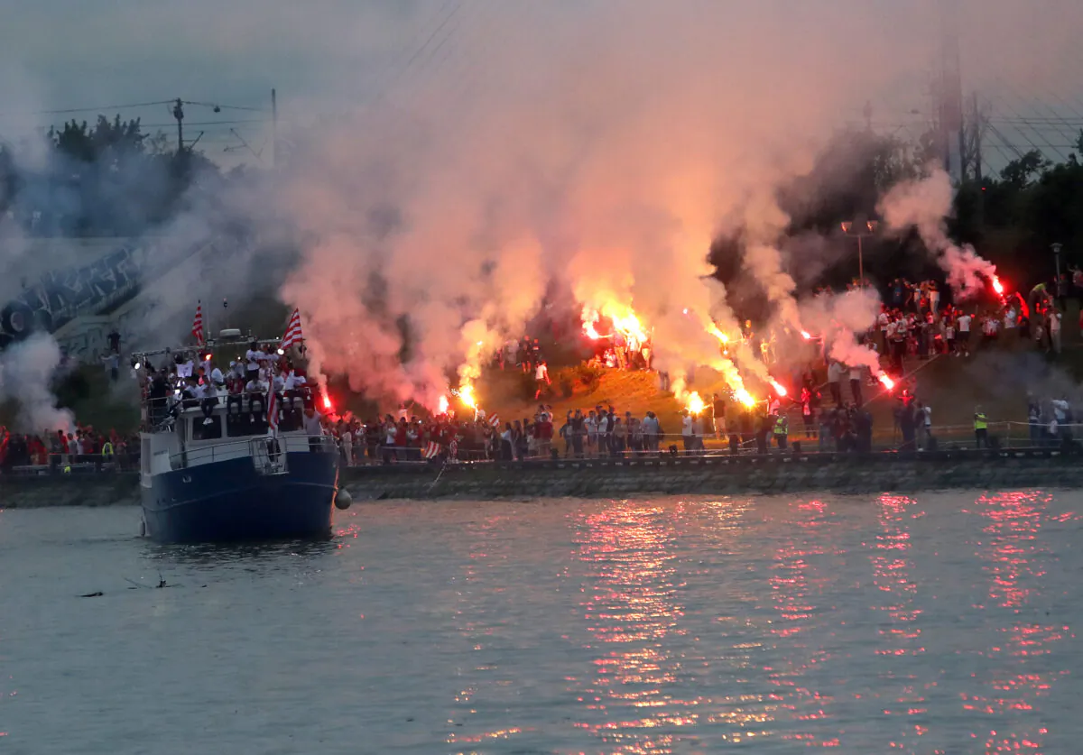 A boat with players cruises on Sava river as Red Star fans celebrate after their team won the Serbian soccer league title in Belgrade, Serbia, on May 22, 2021. (Darko Vojinovic/AP Photo)