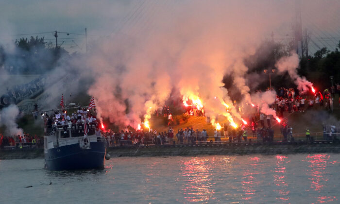 A boat with players cruises on Sava river as Red Star fans celebrate after their team won the Serbian soccer league title in Belgrade, Serbia, on May 22, 2021. (Darko Vojinovic/AP Photo)