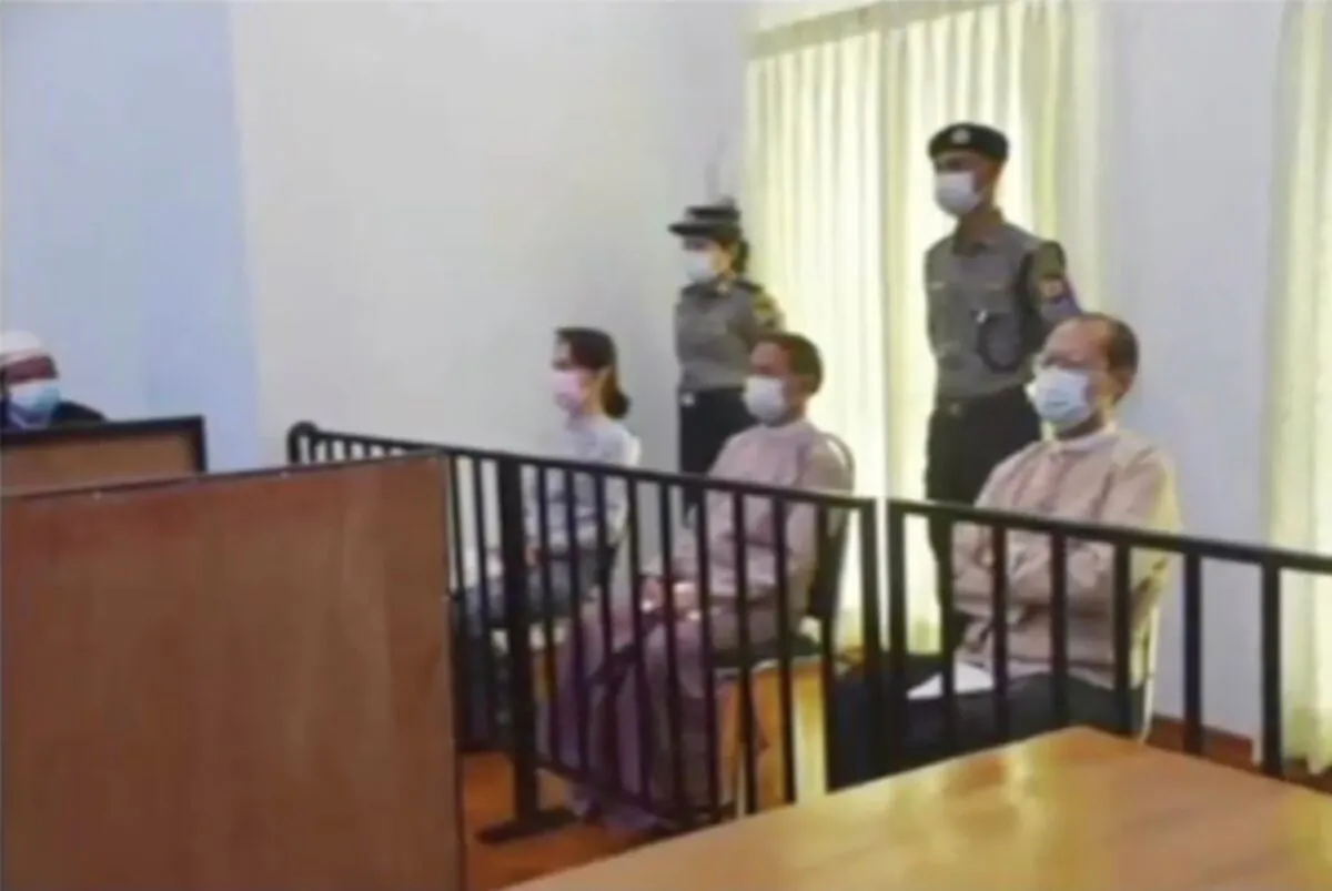 In this image from Myawaddy TV, a photograph shown during a news report showing the appearance of deposed Burma leader Aung San Suu Kyi, former President Win Myint, sitting 3rd from right, and former Naypyitaw Council chairman Dr. Myo Aung before a special court, shown while a report about Suu Kyi's case is read by a news presenter in Naypyitaw, Burma, on May 24, 2021. (Myawaddy TV via AP)