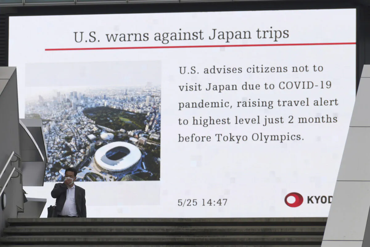A man walks in front of a screen showing the news on U.S. warning against visits to Japan, in Tokyo on May 25, 2021. (Eugene Hoshiko/AP Photo)