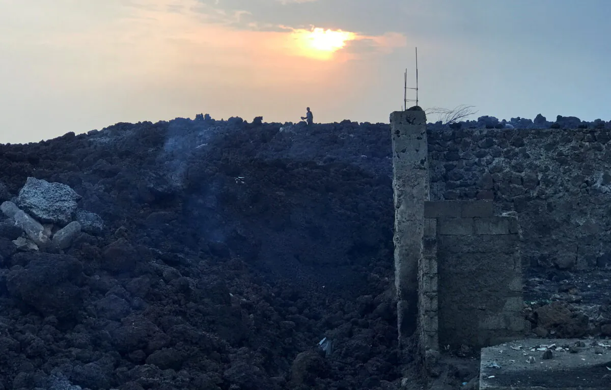 A resident picks up remains from their home which is covered with smouldering lava after the eruption of Mount Nyiragongo volcano, near Goma, in the Democratic Republic of Congo, on May 24, 2021. (Djaffar Al Katanty/Reuters)