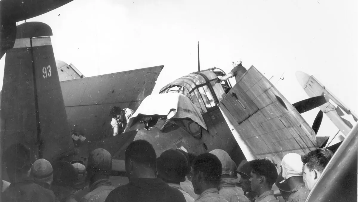 A deck crewman has covered up Loyce Deen while a decision is being made what to do with the aircraft, which sustained heavy battle damage. (Courtesy CDR Michael Cosgrove (Ret.), son of Robert D. Cosgrove via NavSource)