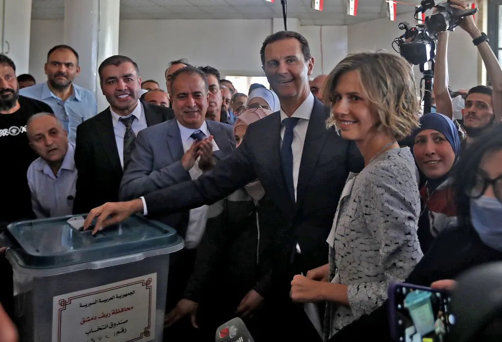 Syrian President Bashar al-Assad (C) and his wife Asma (R) cast their votes at a polling station in Douma, near Damascus, Syria, on May 26, 2021. (Louai Beshara/AFP via Getty Images)