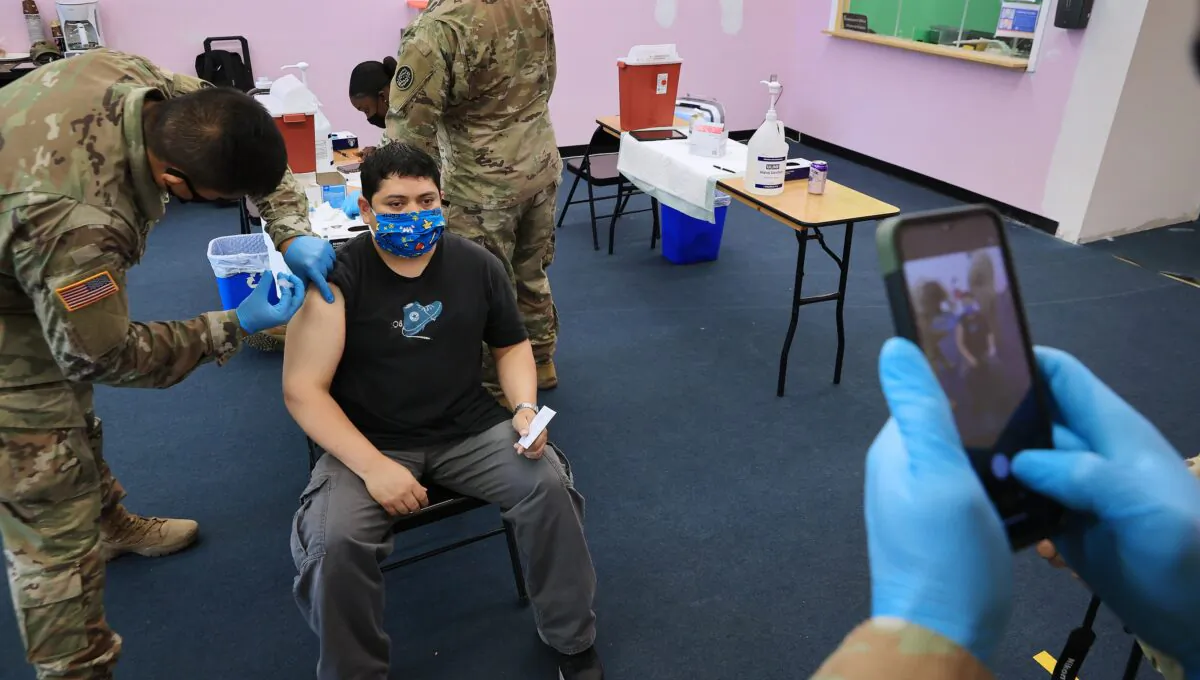 A man asks for his photo to be taken while Maryland National Guard Specialist James Truong gives a Moderna COVID-19 vaccine in Wheaton, Md., on May 21, 2021. (Chip Somodevilla/Getty Images)