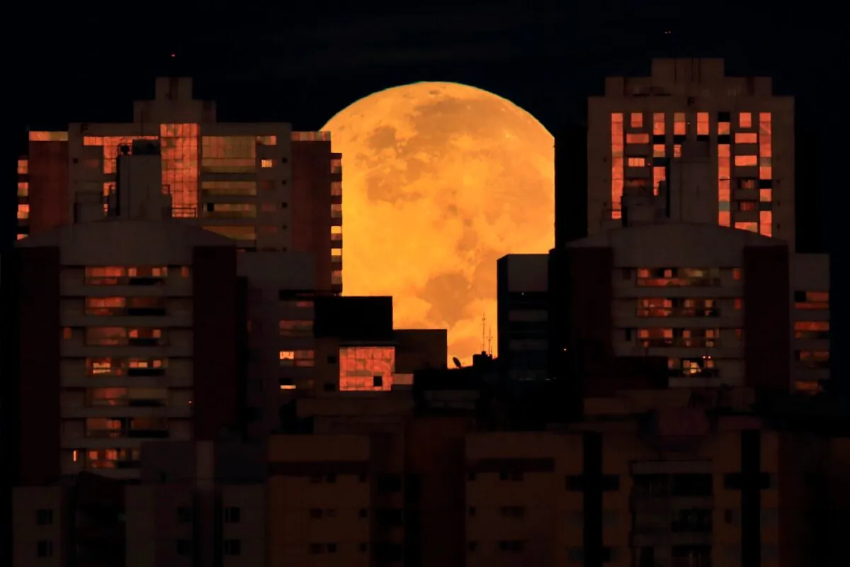 The moon is partially covered by buildings in Brasilia, Brazil, at the start of a total lunar eclipse early on May 26, 2021. (Eraldo Peres/AP Photo)