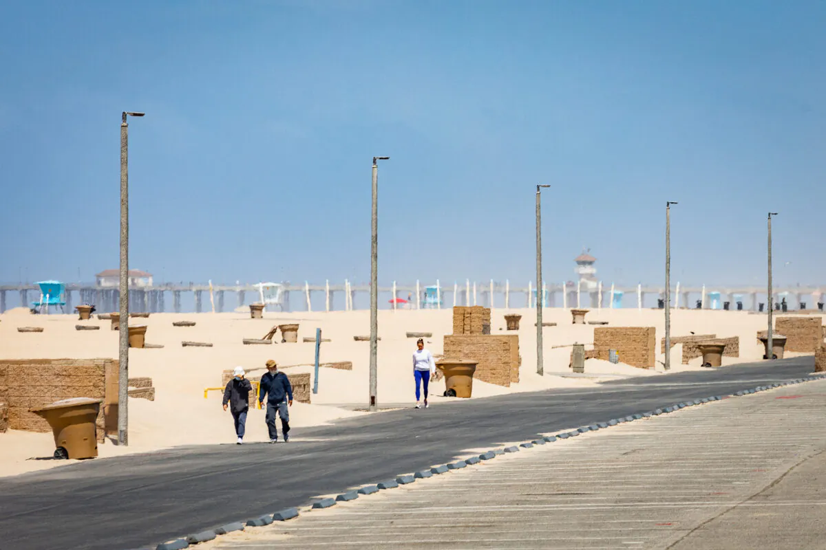 People walk along the beach near lifeguard tower 13 in Huntington Beach, Calif., on May 20, 2021. (John Fredricks/The Epoch Times)