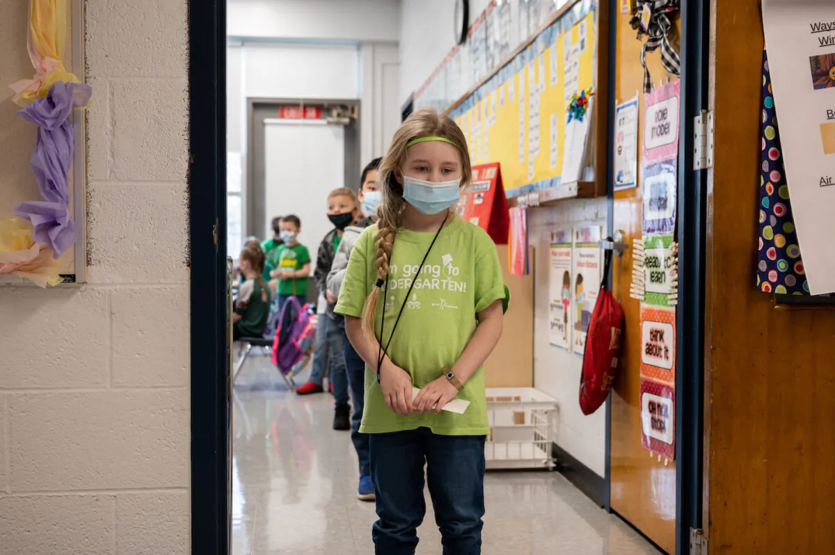 Masked students wait in a socially distanced single file line before heading to the cafeteria at an elementary school in Louisville, Ky., on March 17, 2021. (Jon Cherry/Getty Images)