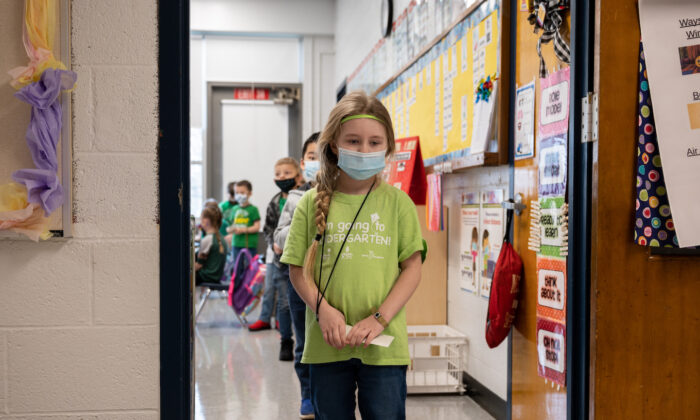 Masked students wait in a socially distanced single file line before heading to the cafeteria at Medora Elementary School in Louisville, Ky., on March 17, 2021. (Jon Cherry/Getty Images)