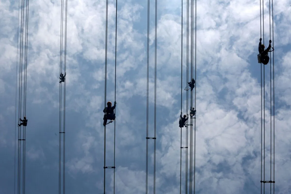 Workers of grid operator China Southern Power Grid inspect power cables connecting transmission towers in Dongguan of Guangdong Province, China, on May 29, 2018. (Stringer/Reuters)