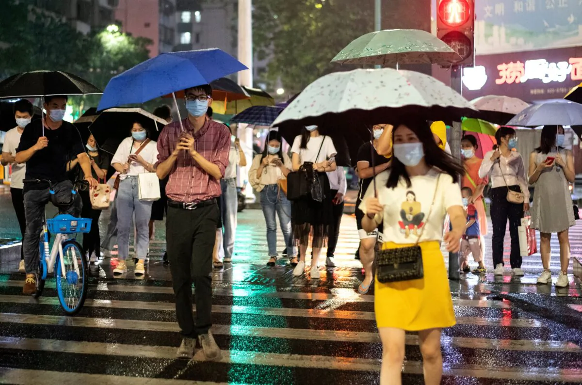 People wearing protective face mask walk under their umbrellas as it rains in Shenzhen in China's southern Guangdong province on May 22, 2020. (Photo by NOEL CELIS/AFP via Getty Images)
