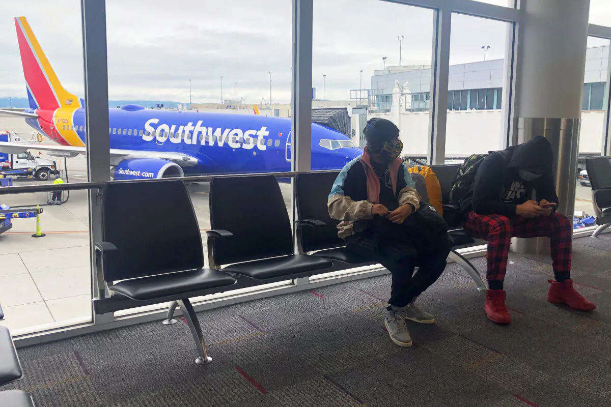 Air travelers wear face masks waiting to board a Southwest Airlines flight at Oakland International airport in Oakland, Calif., on April 9, 2020.  (Shannon Stapleton/Reuters)