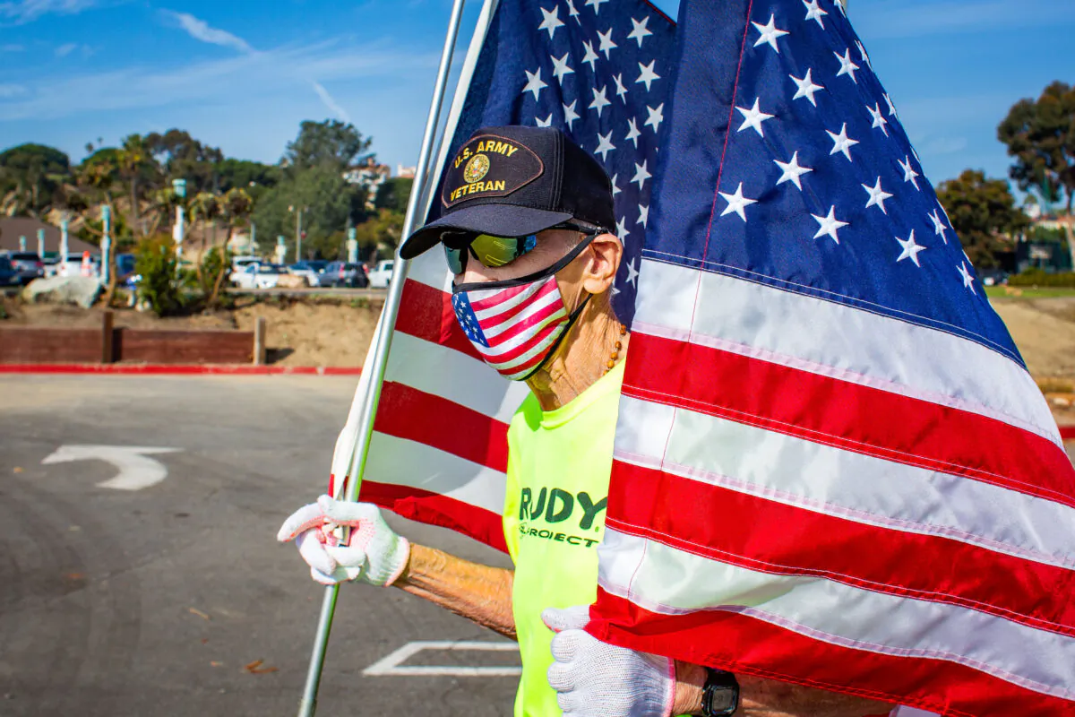 89-year-old runner Robert Kohler runs the virtual 2020 Dana Point Turkey Trot holding two large American Flags in Dana Point, Calif., on Nov. 21, 2020. (John Fredricks/The Epoch Times)