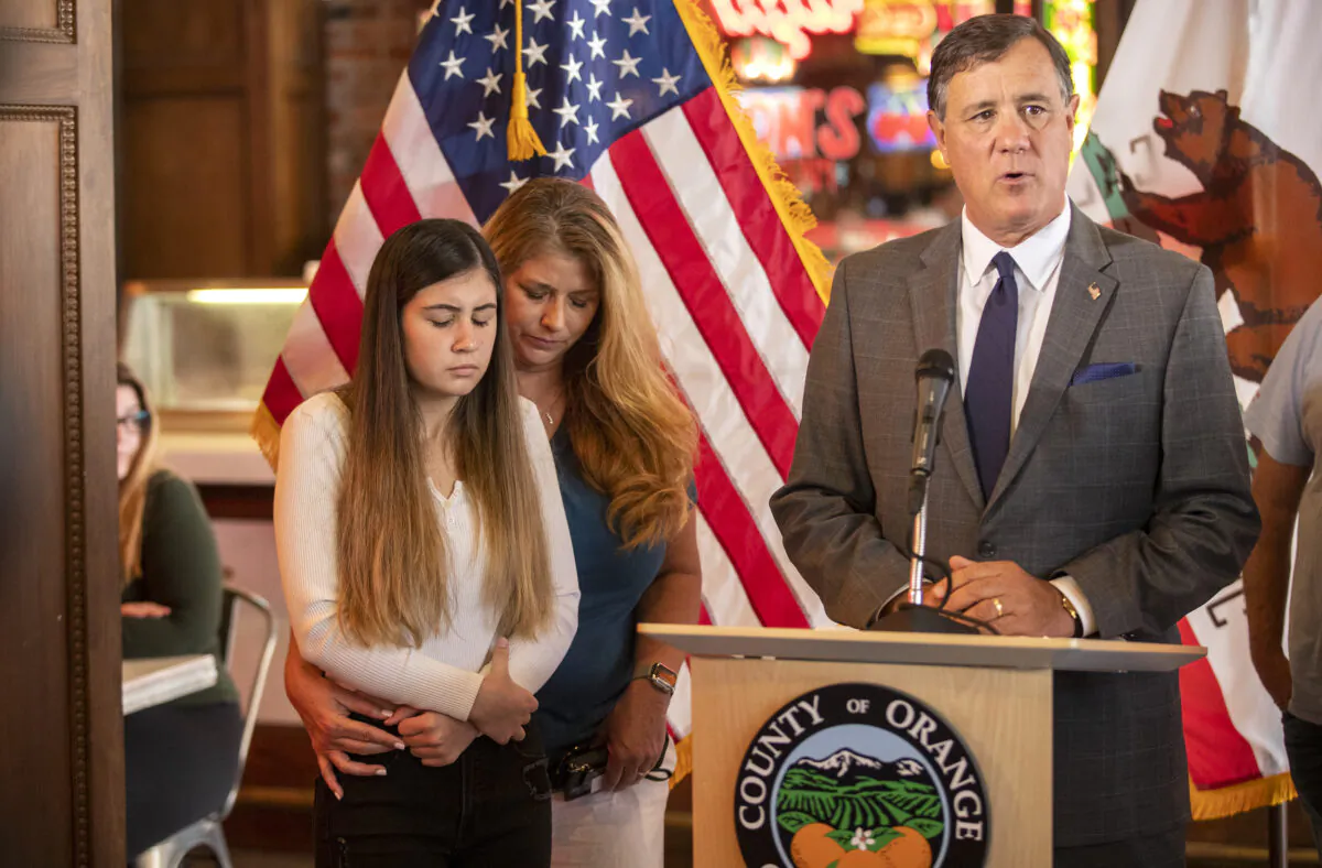 Alexis Cloonan, left, Aiden Leos’ sister, and Carole Ybanez, a family friend, stand behind Orange County Supervisor Don Wagner at a news conference on May 27, 2021 on the freeway shooting that left 6-year-old Aiden dead. (Allen J. Schaben/Los Angeles Times/TNS)