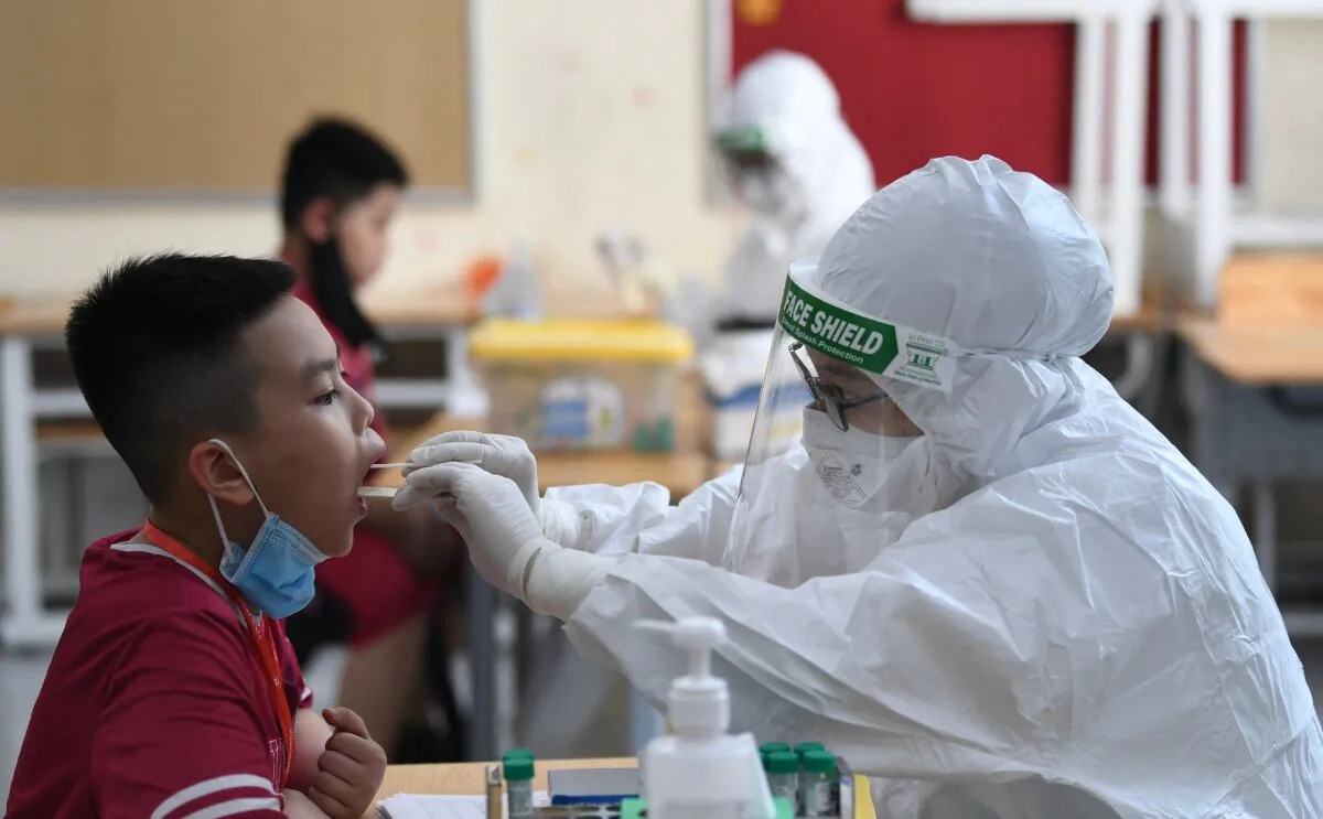 A health worker wearing personal protective equipment (PPE) conducts a COVID-19 swab test on a student at the Vinschool private school in Hanoi, Vietnam, on May 22, 2021. (Nhac Nguyen/AFP via Getty Images)