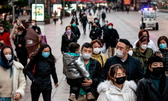 People wearing protective facemasks walk along a street in Shanghai on Feb. 21, 2020. (Noel Celis/AFP via Getty Images)