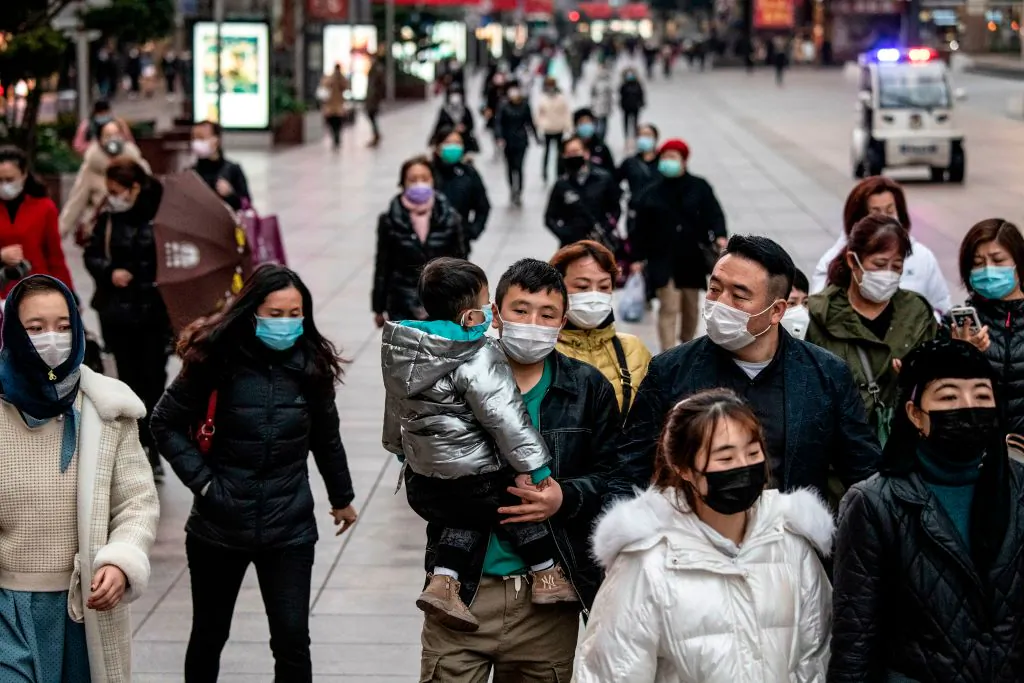 People wearing protective face masks walk along a street in Shanghai, China on Feb. 21, 2020. (NOEL CELIS/AFP via Getty Images)
