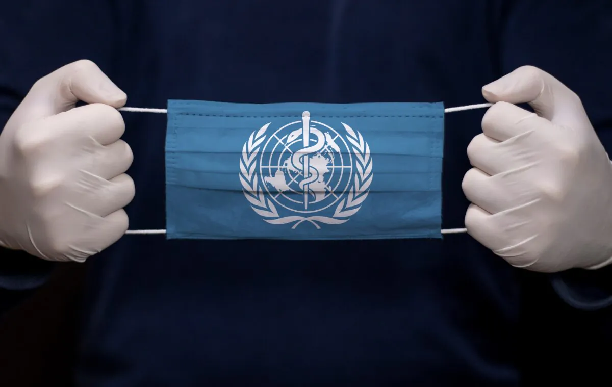 A doctor holds a medical face mask with the World Health Organization's flag. (kcube-Baytur/Shutterstock)