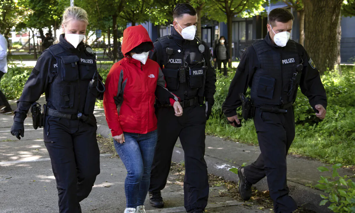 Police officers lead a woman to a vehicle during a raid against a group of people suspect to brought Vietnamese people to Europe on fraudulently obtained visas, in Berlin, on May 31, 2021. (Paul Zinken/dpa via AP)