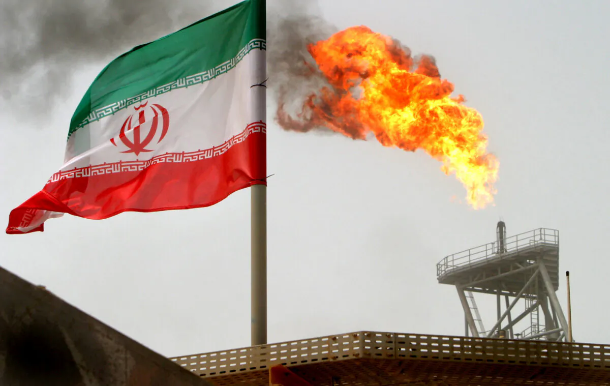 A gas flare on an oil production platform is seen alongside an Iranian flag in the Persian Gulf, on July 25, 2005. (Raheb Homavandi/Reuters)