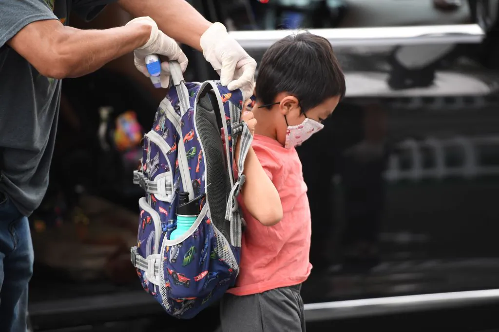 A staff member helps a student put on his backpack at STAR Eco Station Tutoring & Enrichment Center in Culver City, Calif., on Sept. 10, 2020. (Robyn Beck/AFP via Getty Images)