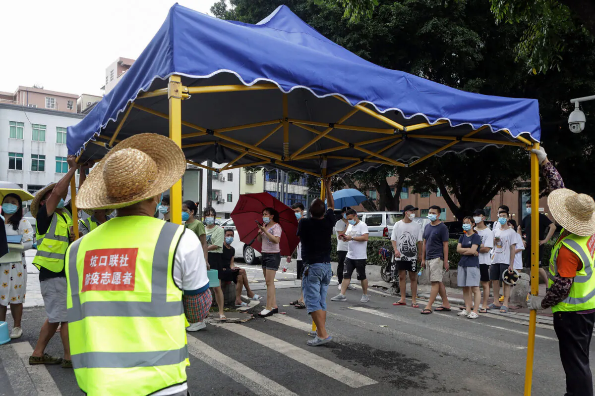 This photo shows volunteers setting up a tent as residents prepare to receive nucleic acid tests for COVID-19 in Guangzhou in China's southern Guangdong province, China. May 30, 2021. (STR/AFP via Getty Images)