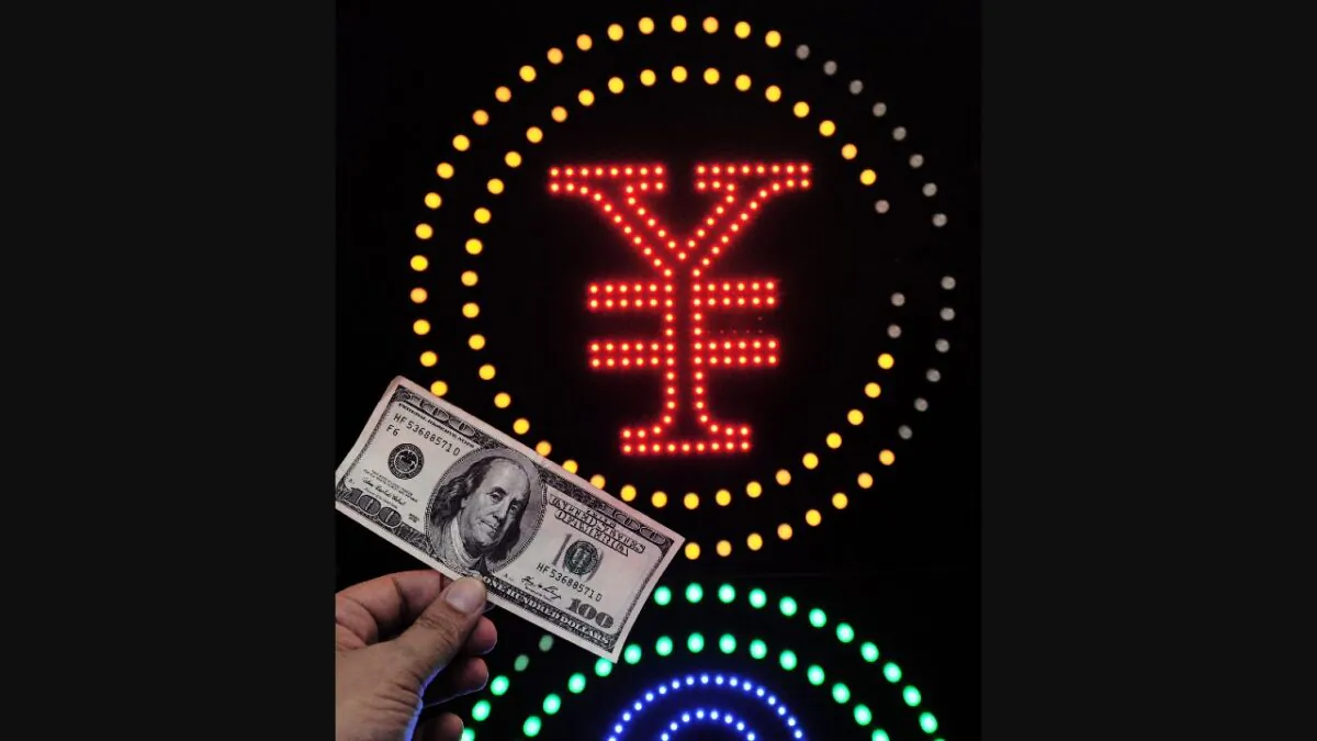 A one hundred U.S. dollar bank note is held in front of a yuan currency sign in Hong Kong, on Oct. 14, 2011. (Laurent Fievet/AFP via Getty Images)