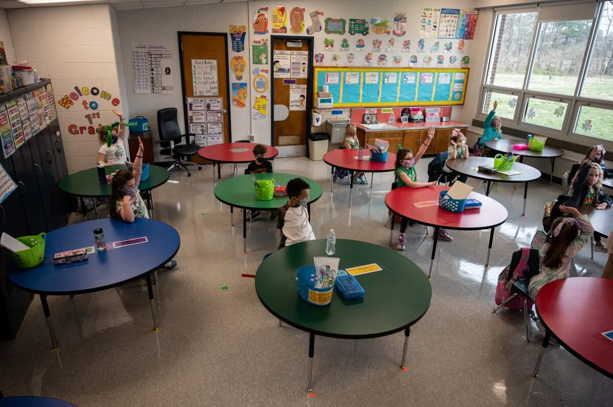 Students raise their hands to answer a teacher’s question during a socially distanced classroom session at Medora Elementary School in Louisville, Ky., on March 17, 2021. (Jon Cherry/Getty Images)