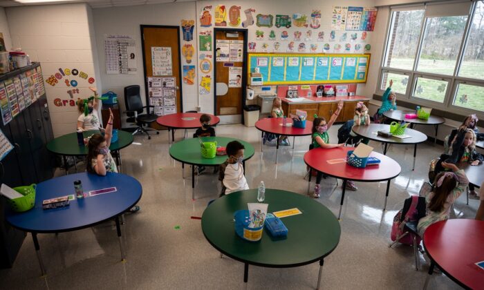 Students raise their hands to answer a teacher’s question during a socially distanced classroom session at Medora Elementary School in Louisville, Ky. on March 17, 2021. (Jon Cherry/Getty Images)
